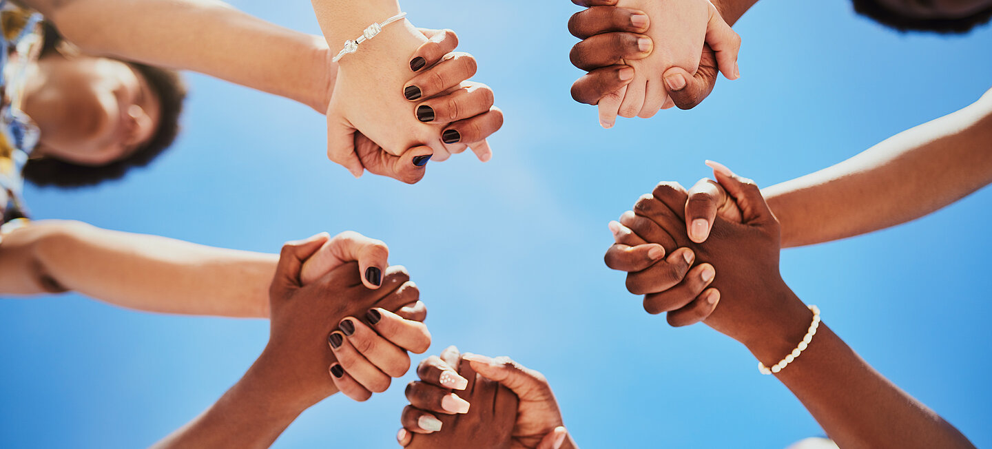 Internationales Team reicht sich die Hände
