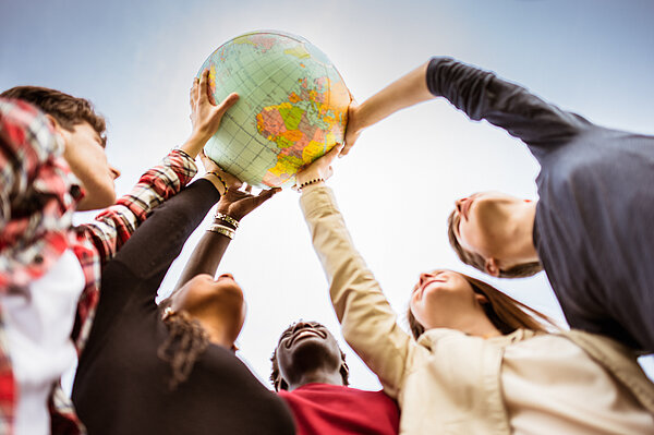 Internationale Studierende Internationale Studierende heben Weltkugel in die Luft