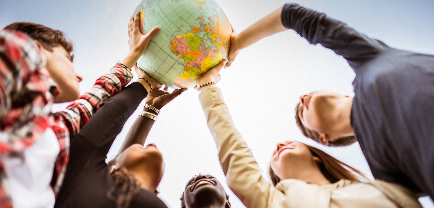 Internationale Studierende heben Weltkugel in die Luft