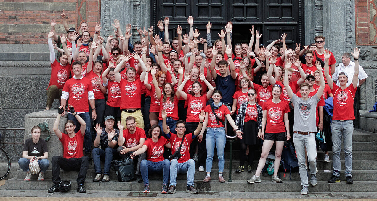 Gruppenbild der Teilnehmenden der HTWK-Radtour in roten Shirts und jubelnd