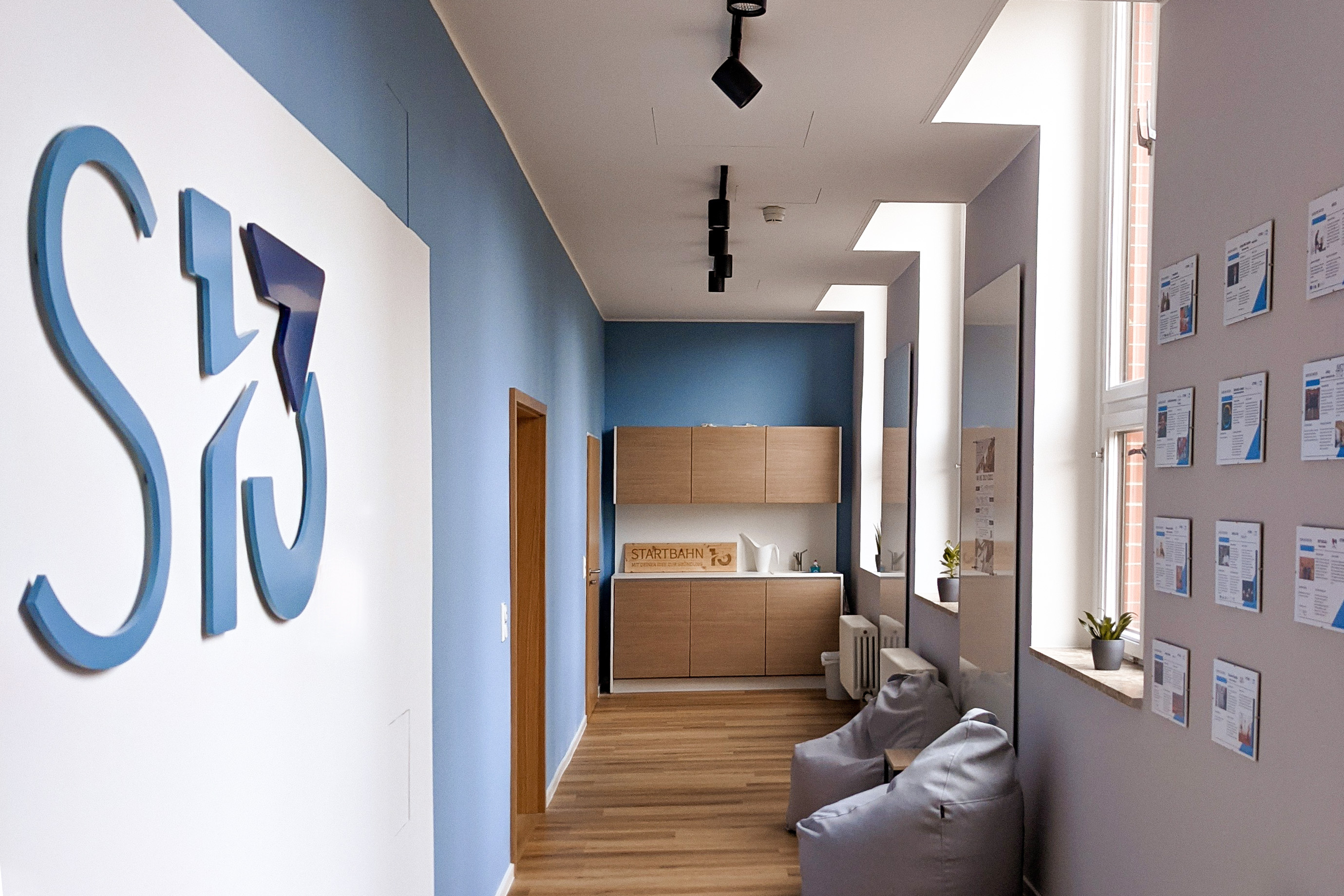 Ansicht des modernen Flur der Gründungsberatung mit einem großen Logo an der Wand, Sitzsäcken und einer kleinen Küchenzeile.